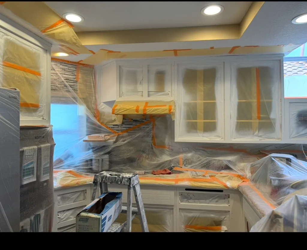 Kitchen cabinets and appliances masked with plastic during painting