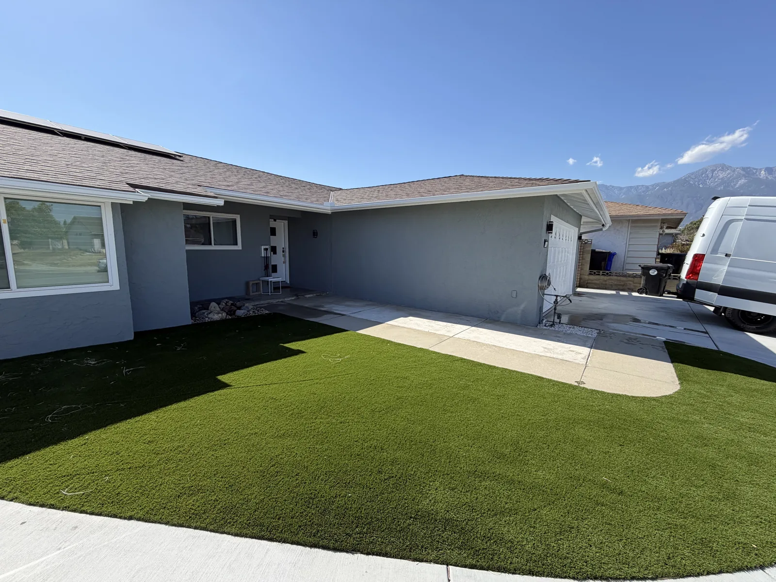 Single-story gray house with white window and garage trim beside a green lawn