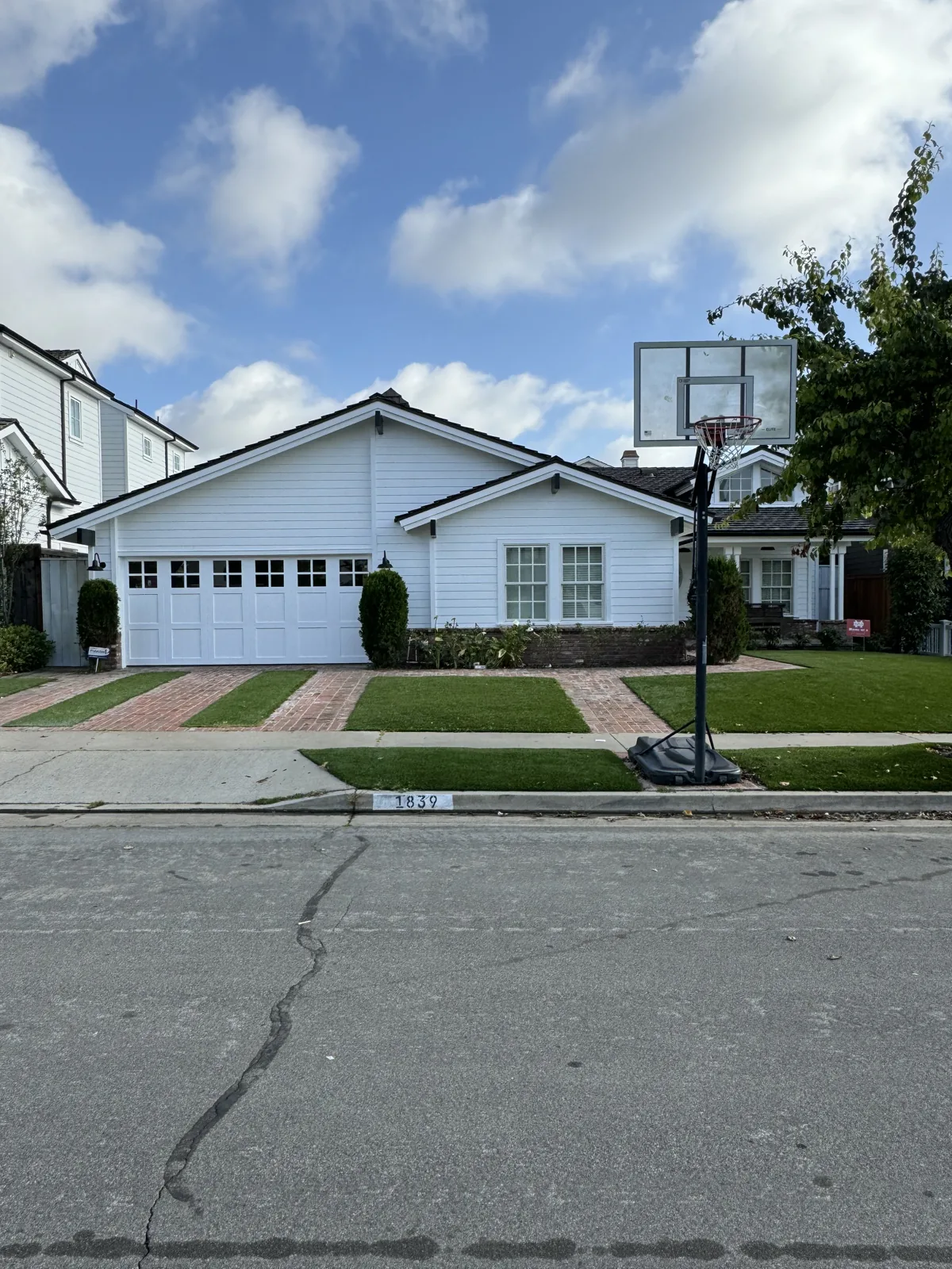 White house with dark roof, front entry and driveway beneath a cloudy sky