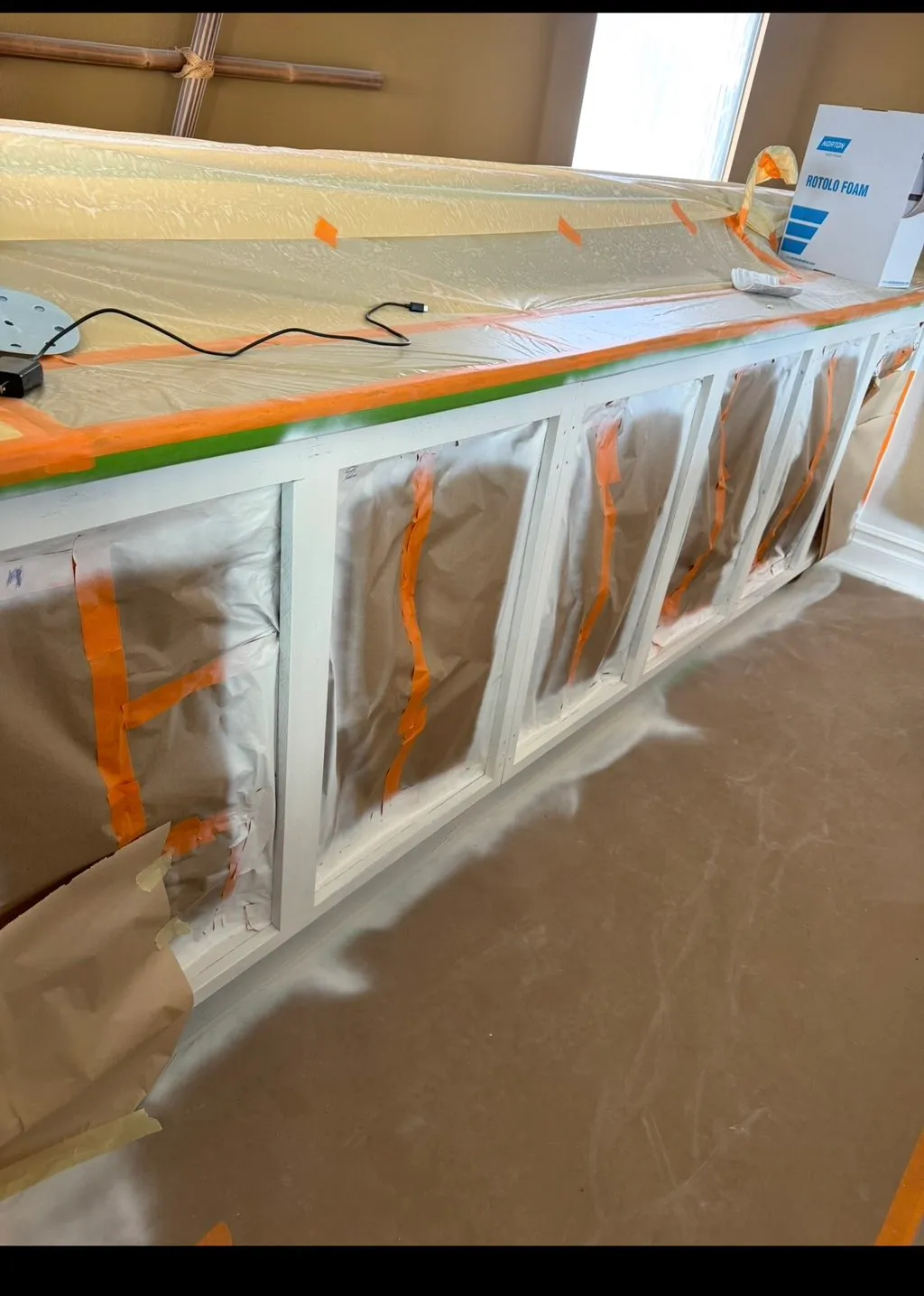 Cabinetry and adjacent woodwork masked and taped before painting