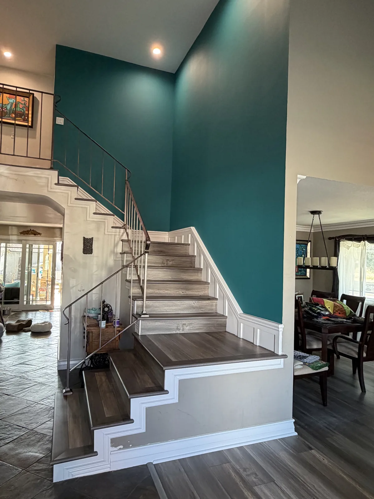 Deep-green interior walls around a white staircase with wood steps and metal railing