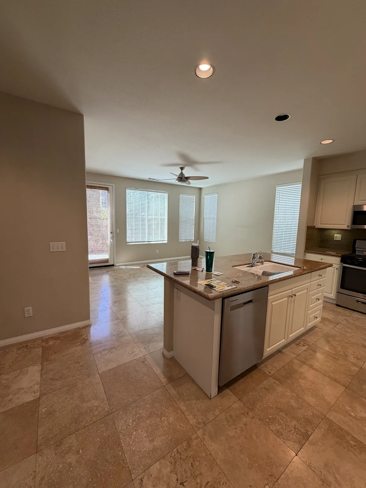 Light-toned kitchen island and cabinetry beside neutral walls and tile flooring